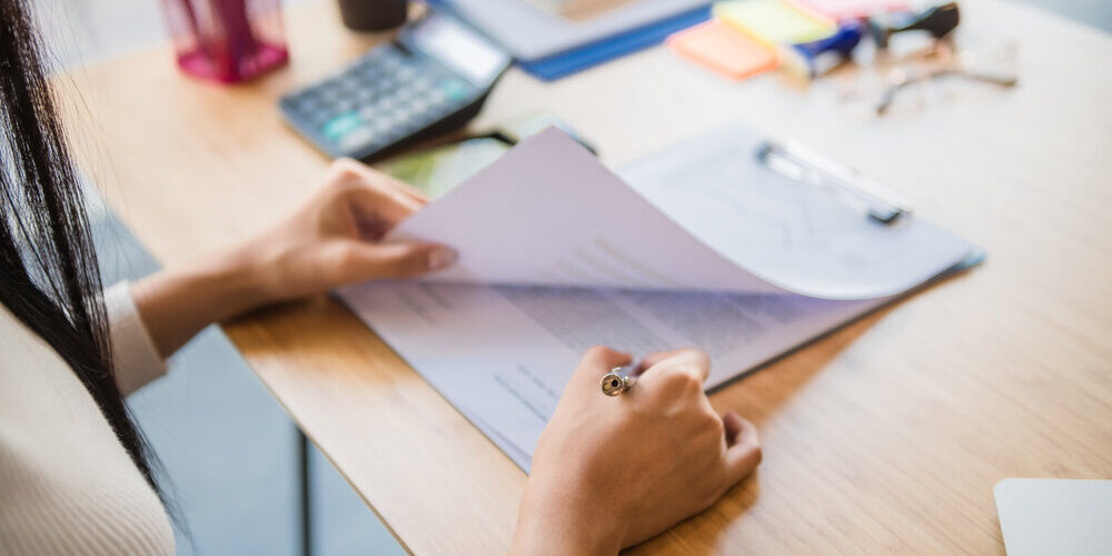 Woman,Signing,Paperwork,,New,Home,In,Background